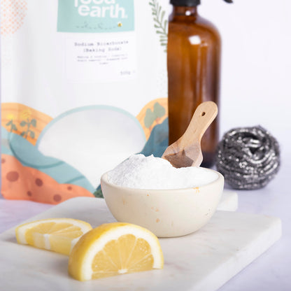 Sodium bicarbonate baking soda in a white container, with a spoon and baking ingredients on a kitchen countertop.