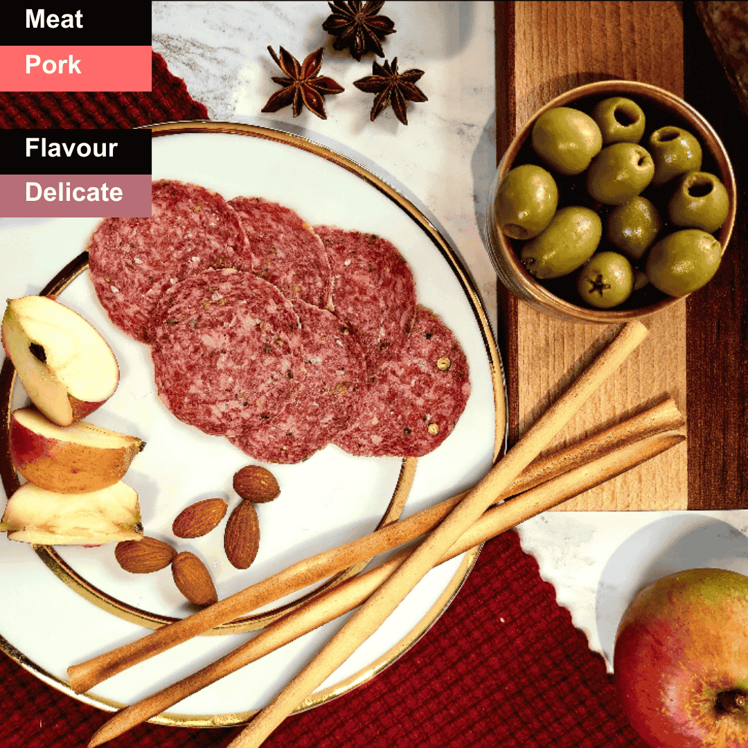 Spicy Bray Cured Fennel Salami slices arranged on a wooden board, showcasing the marbled meat and fennel seeds.