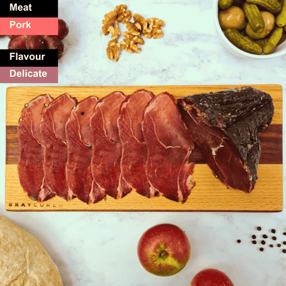 Spicy Bray Cured air-dried ham slices on a wooden board, showcasing the charcuterie's rich texture and vibrant seasoning.