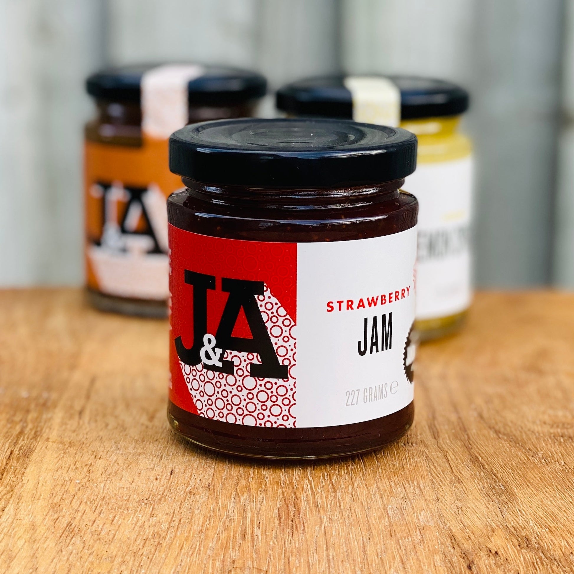 Jar of Janda strawberry jam with fresh strawberries and spread on toast, showcasing the fruit-filled spread.