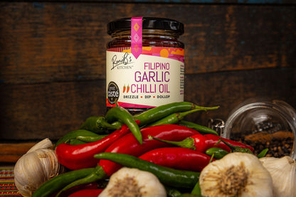 Filipino garlic chili hot sauce by RoniBs Kitchen with vibrant red chili peppers and garlic cloves in a clear glass bottle.