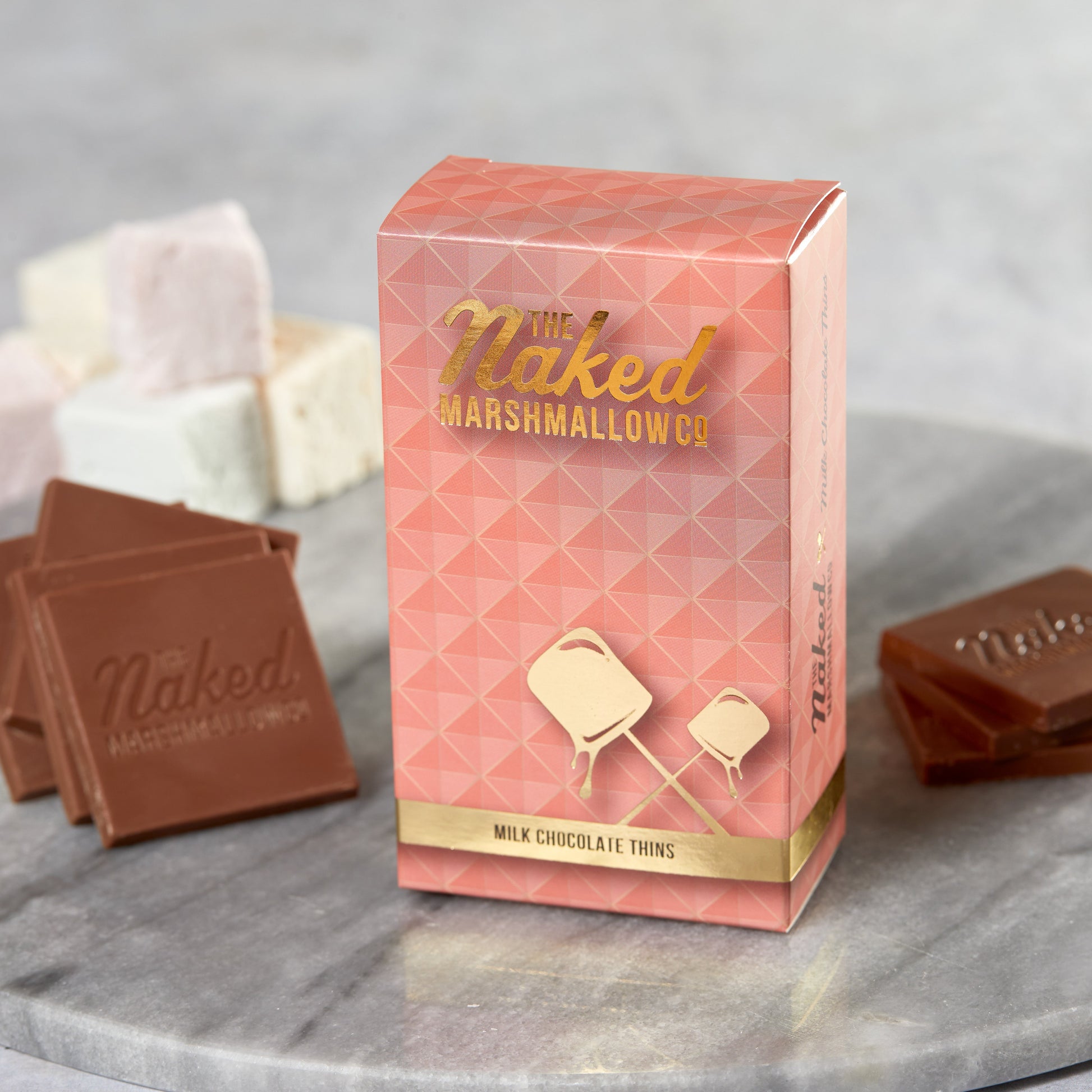 Milk chocolate Thins by THE MARSHMALLOW FACTORY, with a close-up of the thin, smooth chocolate coating on marshmallow treats.