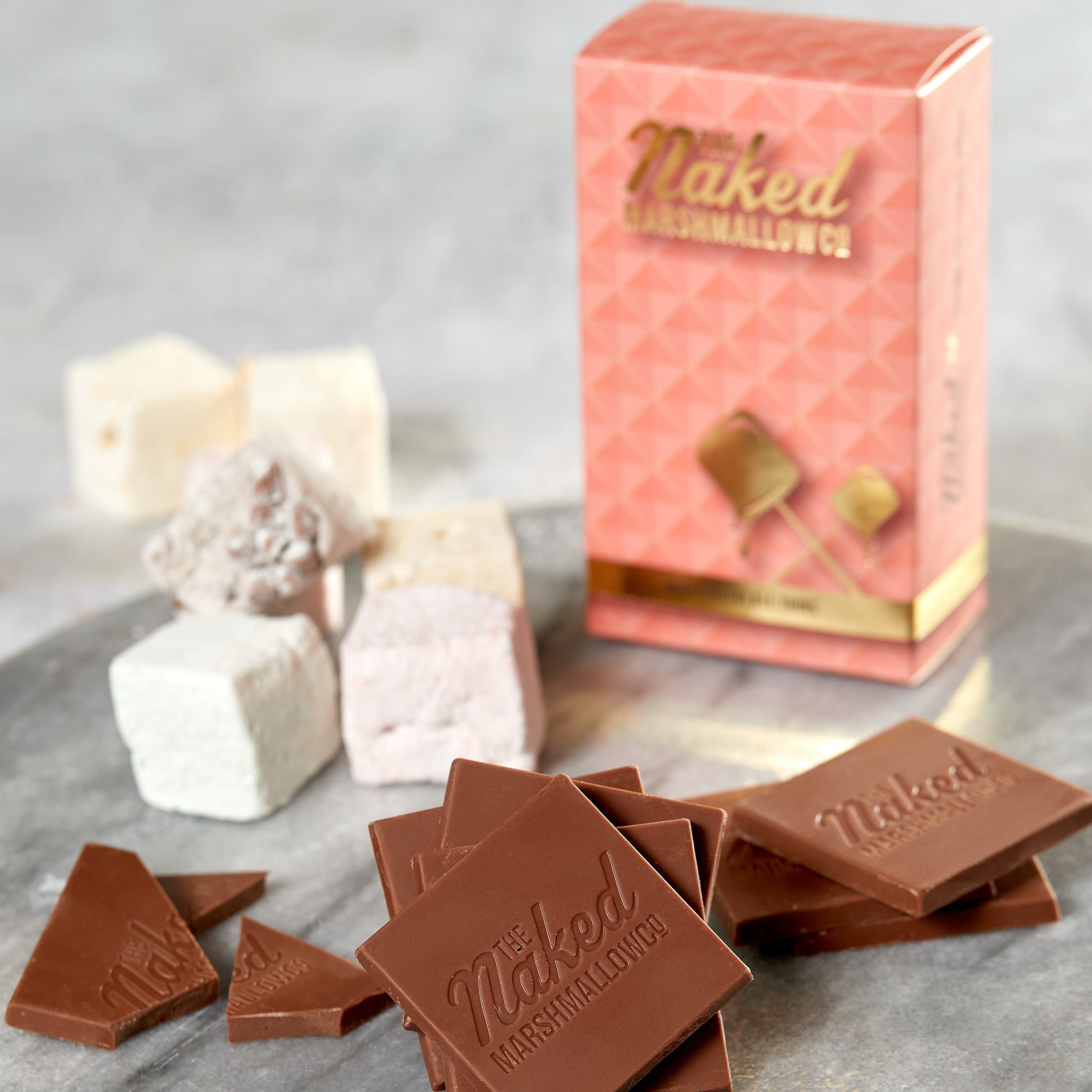 Naked marshmallow surrounded by milk chocolate thins from THE MARSHMALLOW FACTORY, close-up view of the snack.