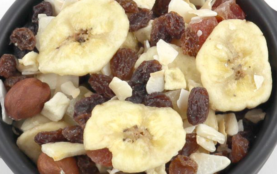 Assorted dried tropical fruits and nuts in a specialty blend from Whole Food Earth, displayed in a clear bowl.
