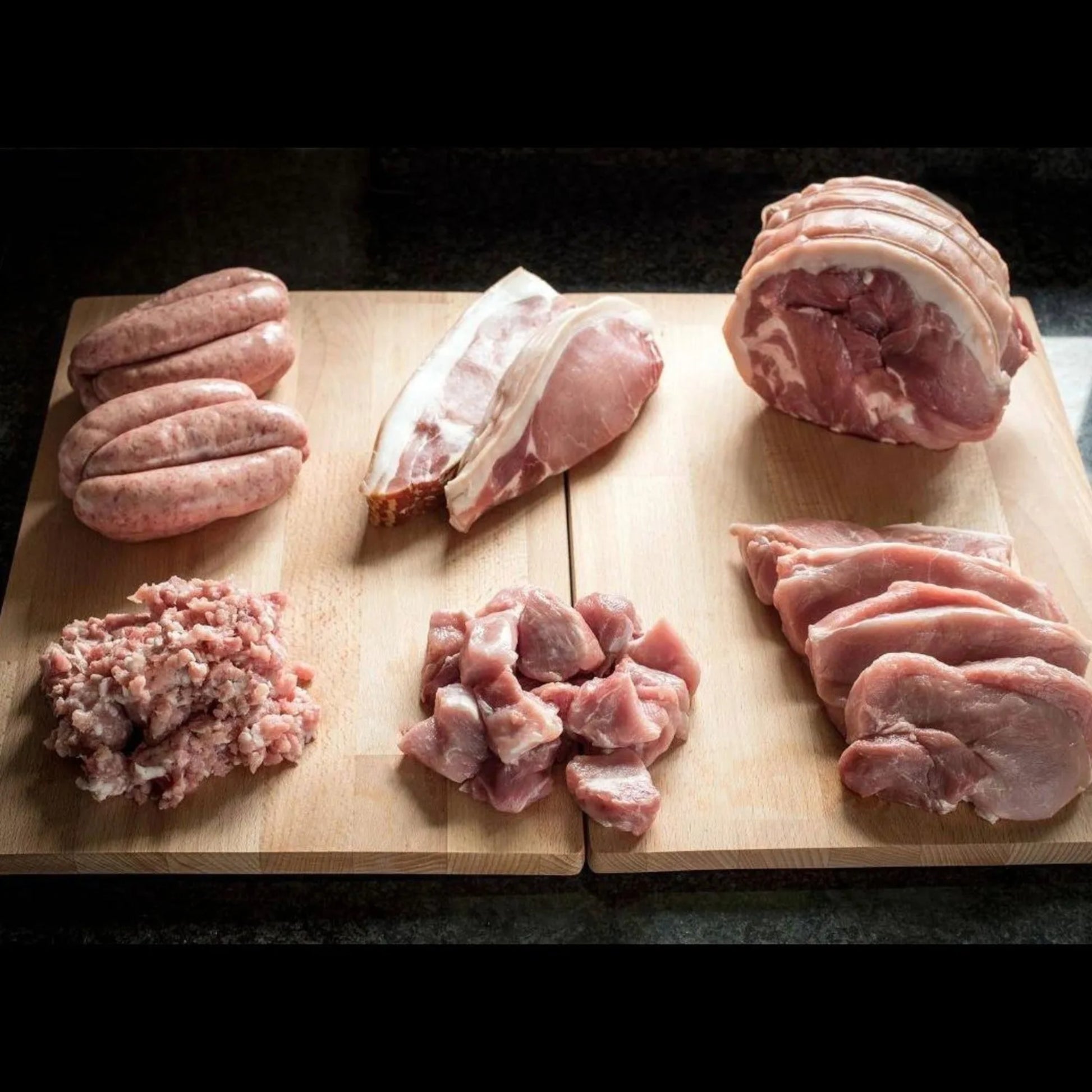 Primrose Herd Cornish outdoor-reared heritage pork taster box with assorted cuts, displayed in a rustic meat box.