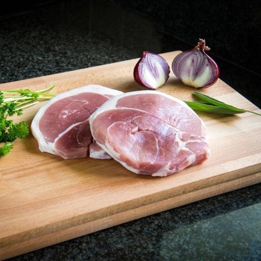 Primrose Herd Cornish outdoor-reared pork gammon steaks, raw pork steaks showing marbled meat and bone-in cut on a wooden surface.