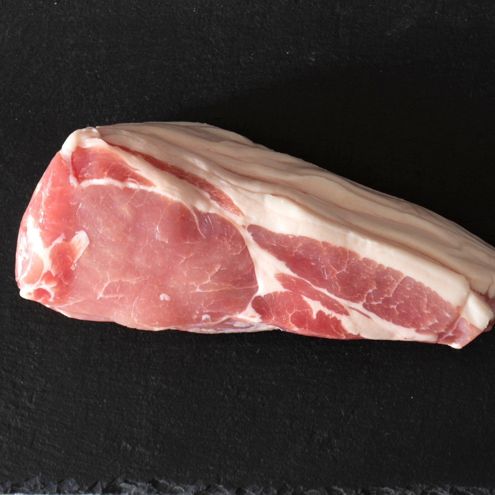 Primrose Herd Cornish Heritage Pork dry-cured smoked back bacon slices on a cutting board, showcasing crispy, golden-brown bacon.