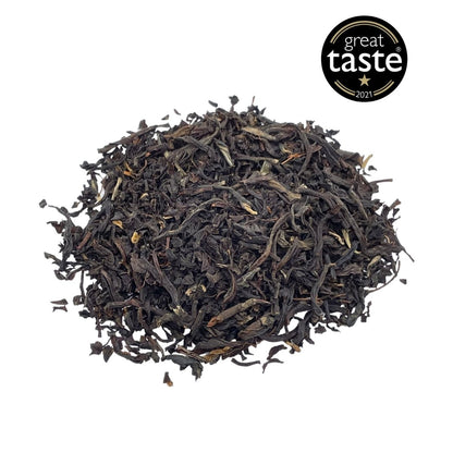 Loose leaf English Breakfast tea by Camellios with dark tea leaves and a rustic tea tin in the background.