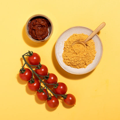 Organic tomato powder from Wild Elephant, packaged in herbs and spices, displayed in a clear container with a natural background.