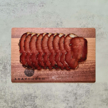 Thin slices of Bray Cured air-dried ham on a wooden board, showcasing the rich marbling and artisanal charcuterie presentation.