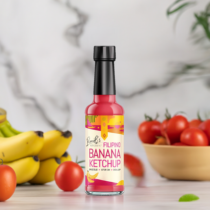 RoniBs Kitchen Filipino Style Banana Ketchup bottle with bananas and tomatoes around it, showcasing the sweet and tangy condiment.