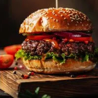 Cooked Primrose Herd grass-fed beef burger with melted cheese and fresh toppings on a bun, ready to serve.