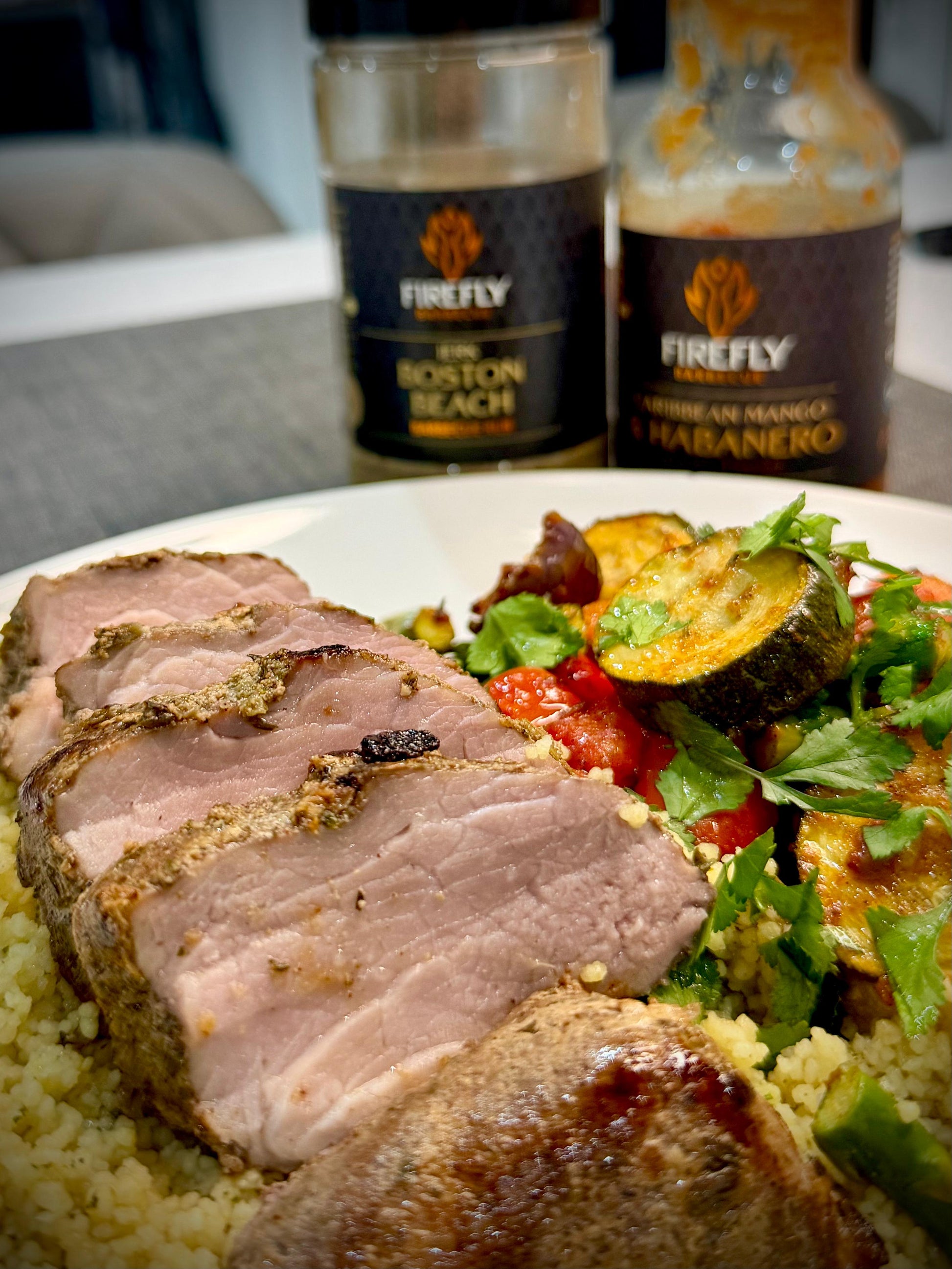 FireFly Barbecue Boston Beach Jerk Rub for BBQ, shown on a lamb cut, featuring a flavorful spice blend in a jar.