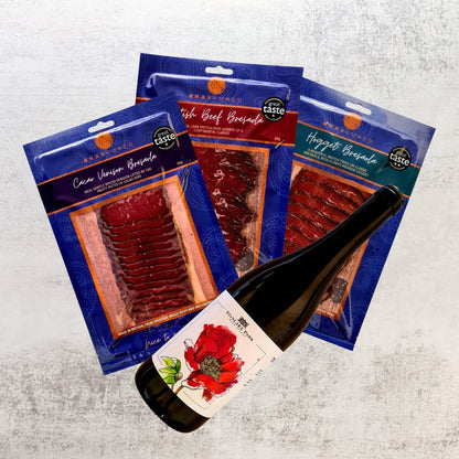 Bray Cured Bresaola Trio and British Red Wine Tasting Hamper with sliced cured meats and a bottle of red wine on a wooden board.