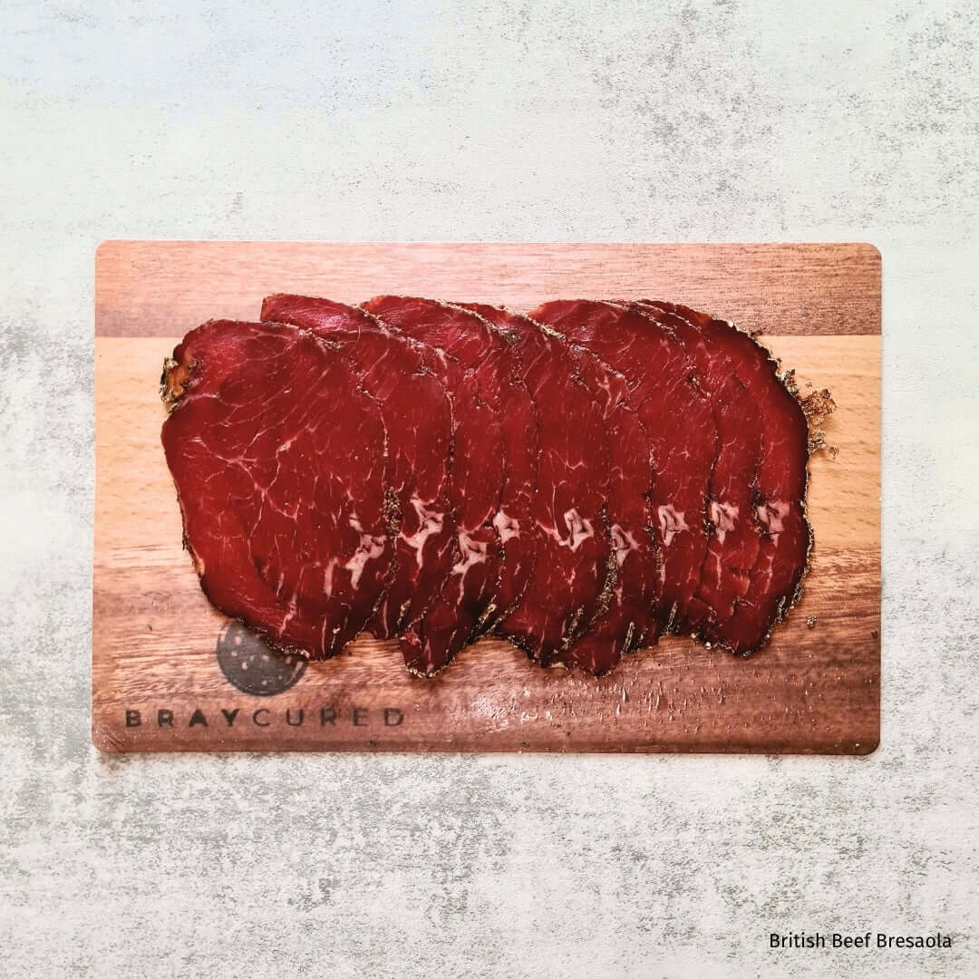 British beef Bresaola slices on a charcuterie board with complementary items, paired with British Red Wine in an elegant hamper by Bray Cured.