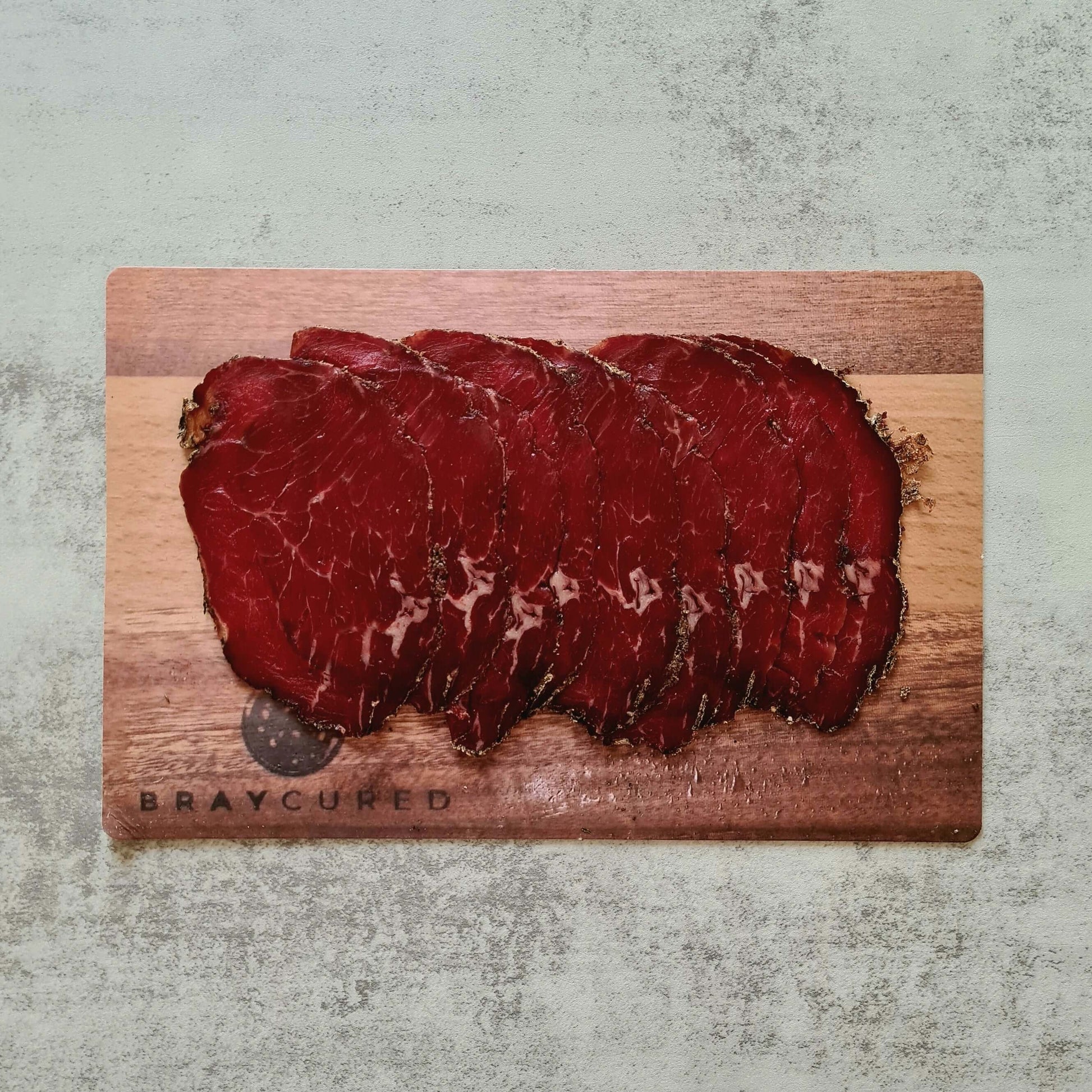 Thinly sliced Bray Cured Classic Bresaola on a charcuterie board with herbs and accompaniments, showcasing premium British beef.