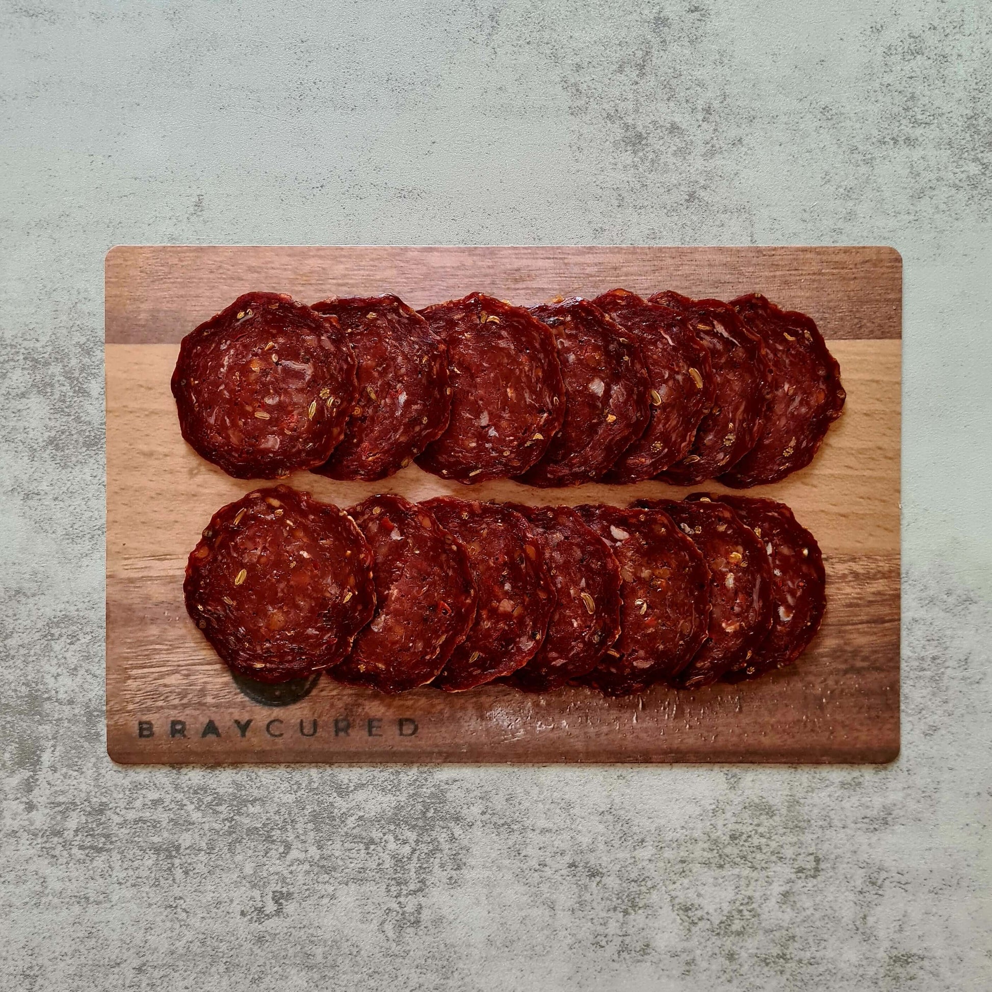 Sliced British Pepperoni from Bray Cured on a charcuterie board with cheese and crackers, showcasing its rich, flavorful appearance.