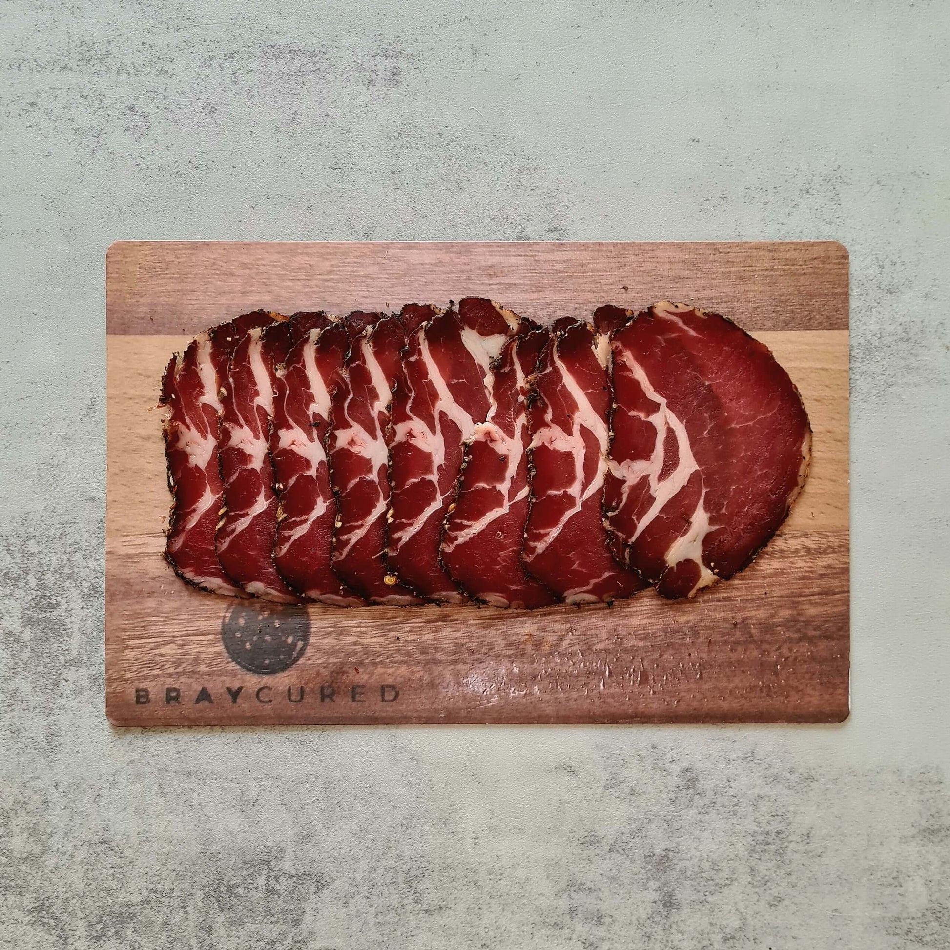 Thin slices of Bray Cured Air-Dried Coppa on a charcuterie board, showcasing its marbled, cured Italian pork meat.