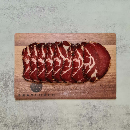 Thin slices of Bray Cured Air-Dried Coppa on a charcuterie board, showcasing its marbled, cured Italian pork meat.