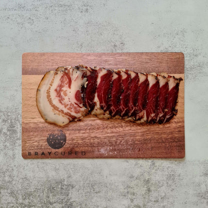 British guanciale from Bray Cured on a charcuterie board, showcasing its slices and rich, marbled pork fat.