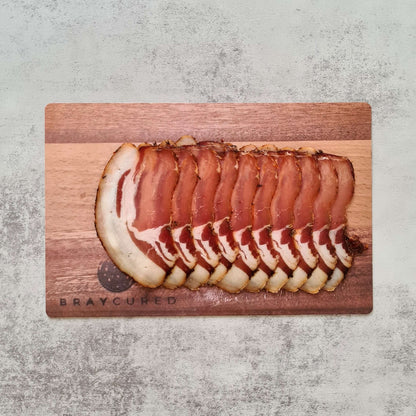 Sliced Bray Cured Classic Lomo charcuterie on a wooden board, showcasing rich, cured British meat with herbs and spices.