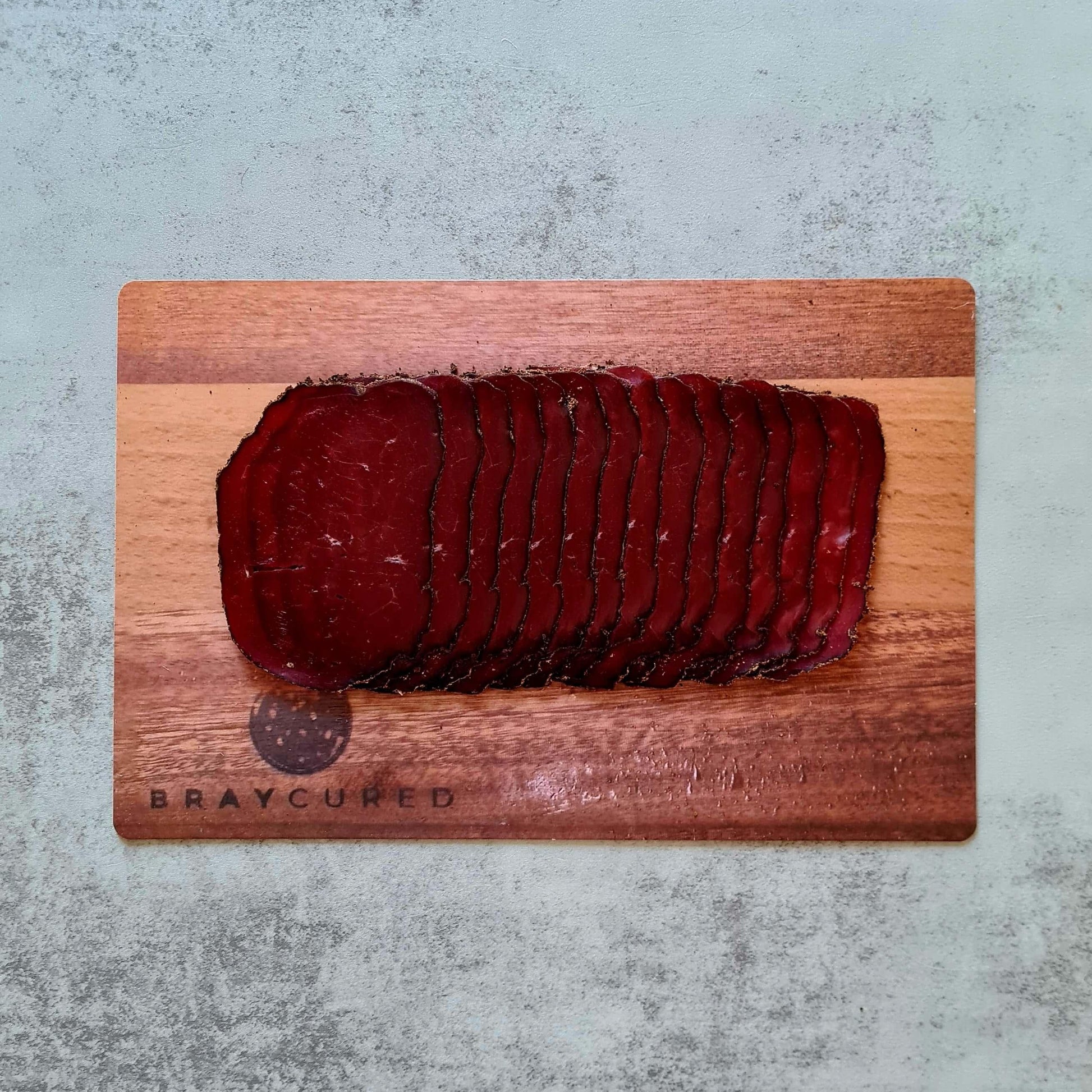 Thin slices of cacao-spiced venison bresaola from Bray Cured served on a charcuterie board with accompaniments.
