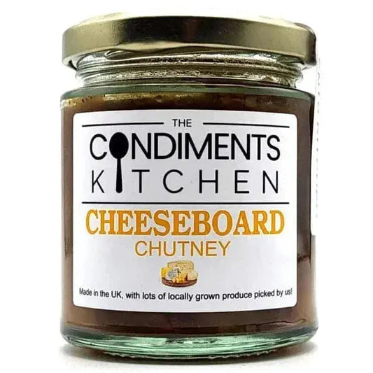 A cheeseboard with assorted cheeses, crackers, and a jar of chutney from The Condiments Kitchen, perfect for cheese pairing.