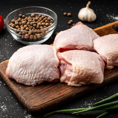 Primrose Herd Creedy Carver free-range chicken thighs with bone, showing fresh, raw chicken thighs on a cutting board.