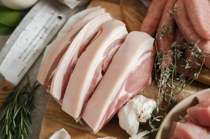 Assorted pork chops from Primrose Herd Family Pork Box, showcasing fresh, uncooked meat cuts on a white background.