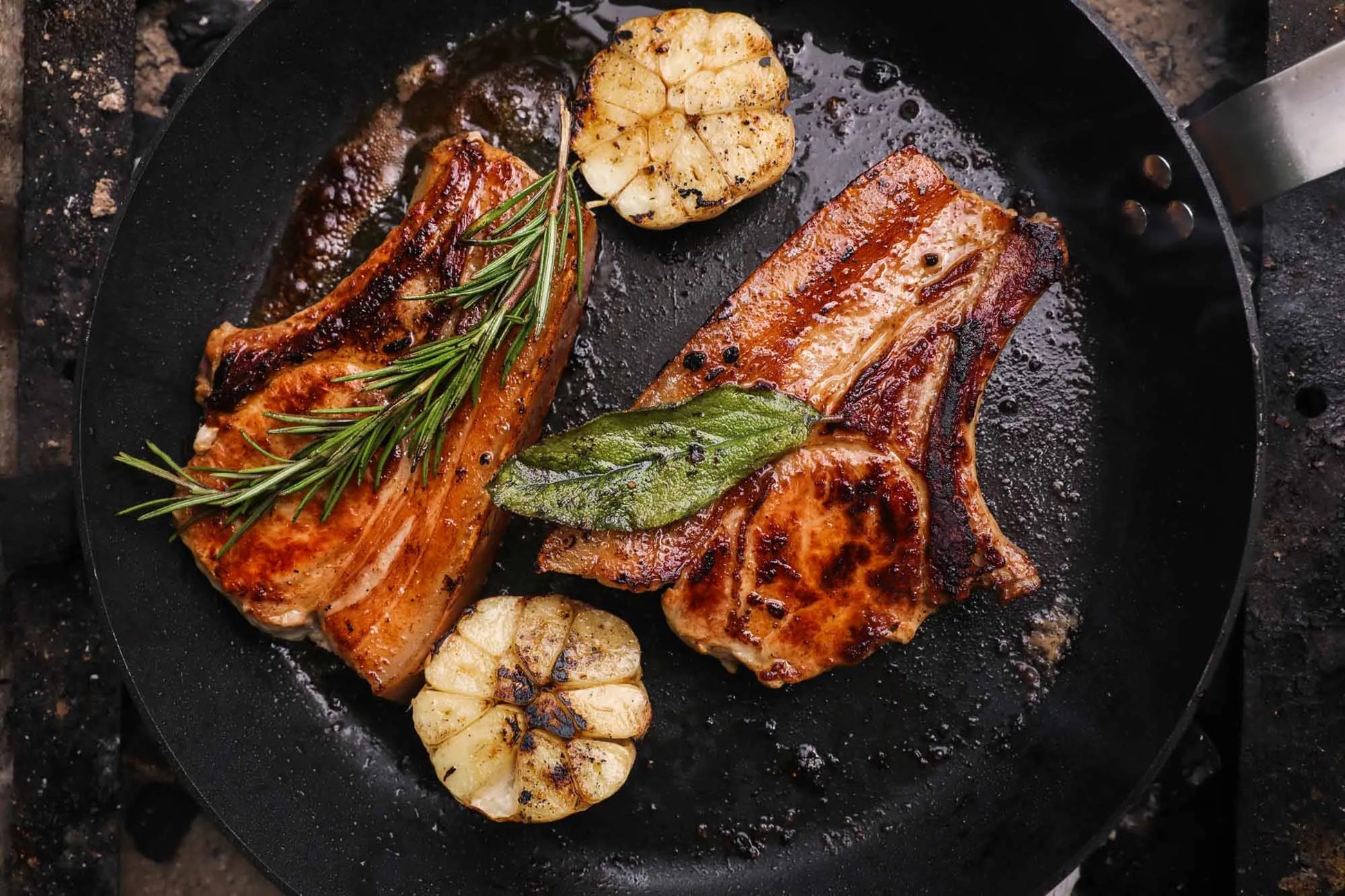Two beef chops sizzling in a pan, part of the Primrose Herd Family Meat Box, showcasing fresh, cooked meat cuts.