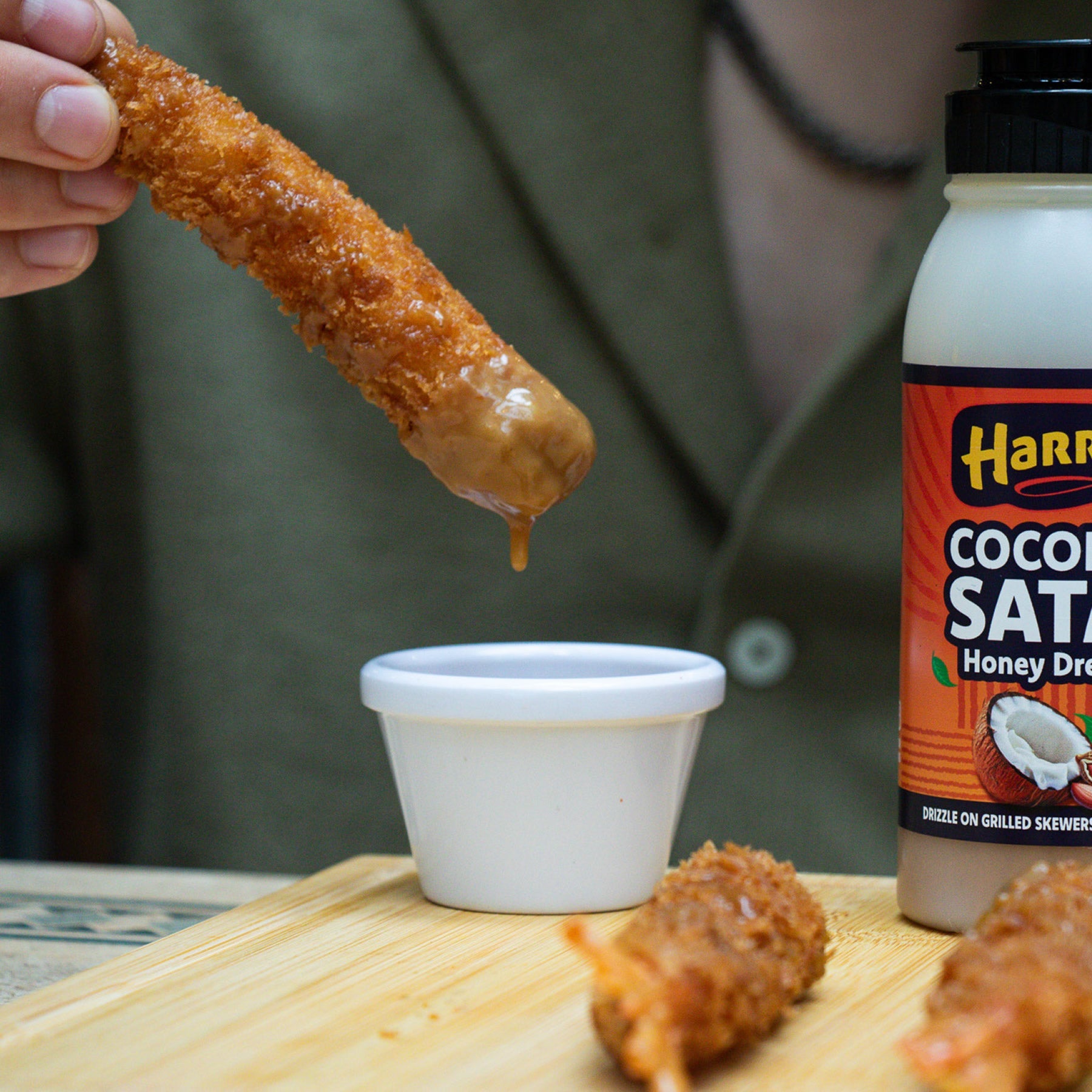 Harry's Hot Honey Coconut Satay Honey Dressing drizzled over crispy bites, showcasing the creamy coconut and rich honey flavors.