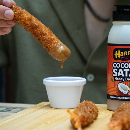 Harry's Hot Honey Coconut Satay Honey Dressing drizzled over crispy bites, showcasing the creamy coconut and rich honey flavors.
