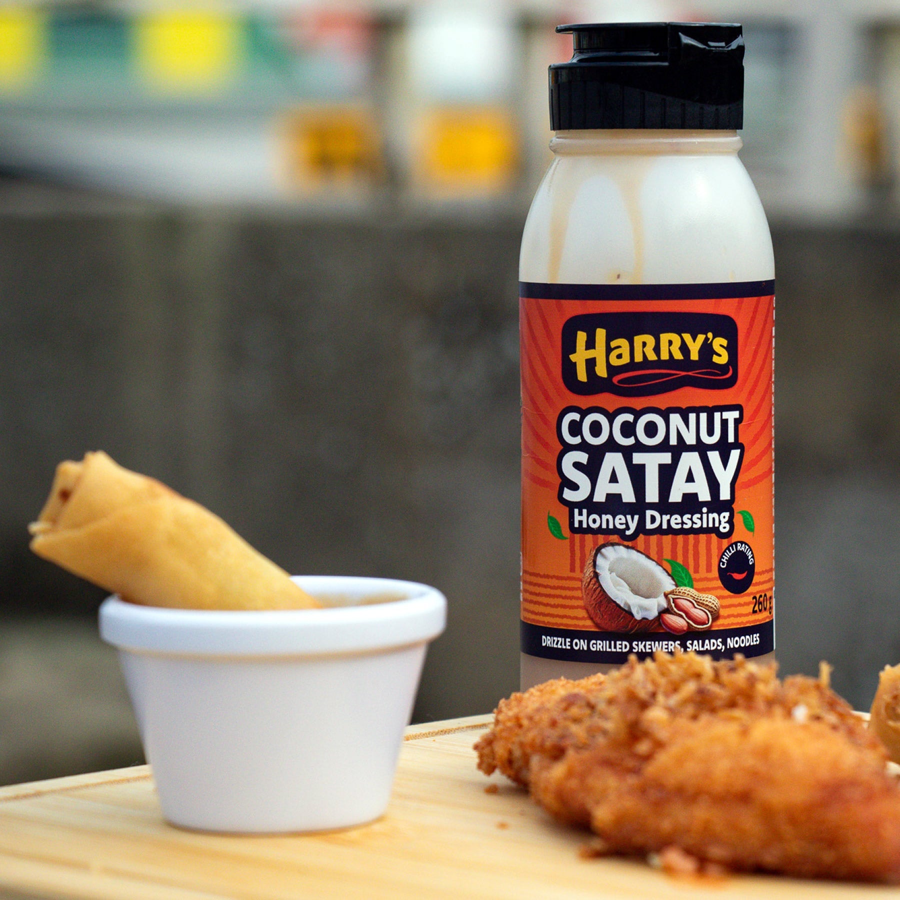 Coconut Satay Honey Dressing by Harry's Hot Honey drizzled over spring rolls, showcasing a creamy, tropical-inspired sauce.
