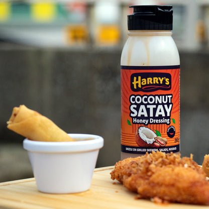 Coconut Satay Honey Dressing by Harry's Hot Honey drizzled over spring rolls, showcasing a creamy, tropical-inspired sauce.