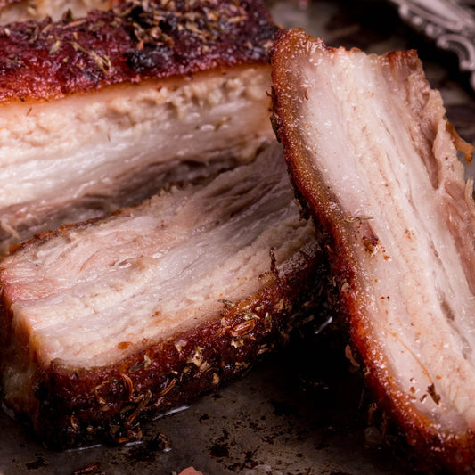 Cooked Primrose Herd pork belly slices showing tender, crispy pork belly slices on a serving plate.