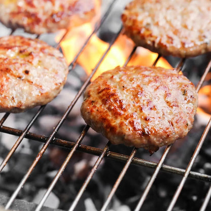 Cooked Primrose Herd pork and apple burgers plated with fresh greens, showcasing the savory pork burger with apple slices.