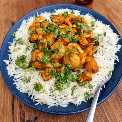 Spicy New Orleans Creole BBQ sauce from FireFly Barbecue served with prawns and jambalaya, showcasing rich, flavorful ingredients.