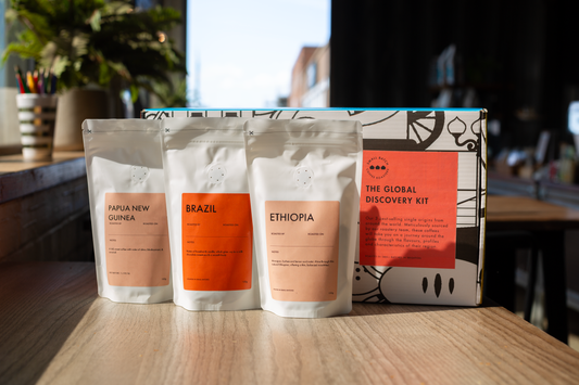 ArtisanBox Global Discovery Kit with single origin tasting set featuring various small coffee or tea samples in individual cups.