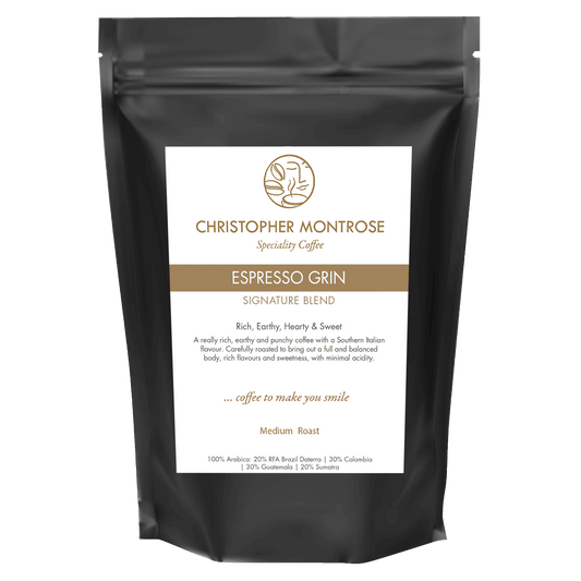 Close-up of Christopher Montrose Coffee Espresso Grin Arabica coffee beans in a transparent bag, showcasing rich brown beans and natural texture.