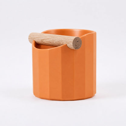 KNOCDIC® Facet Geometric Espresso Knock Box with orange exterior and oak knock bar for coffee filter disposal.