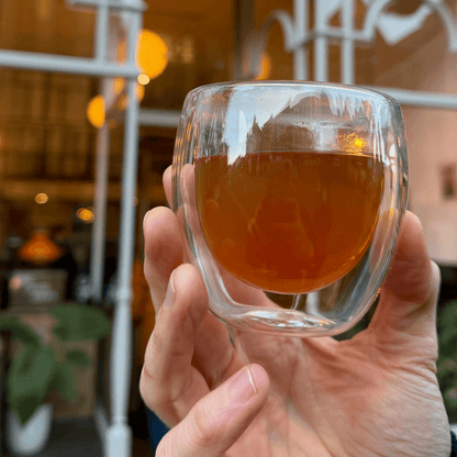 Brewed Formosa Oolong tea in a clear glass cup, showcasing its amber color and delicate floral aroma from Porter Hill Tea Company.