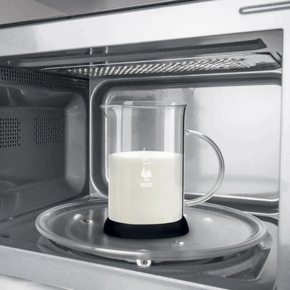 Bialetti Tuttocrema glass milk frother with a clear glass body and stainless steel lid, used for frothing milk.