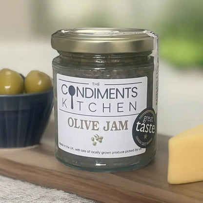 The Condiments Kitchen Olive Jam 195g chutney jar with label, showcasing glossy green olives and rich jam texture.