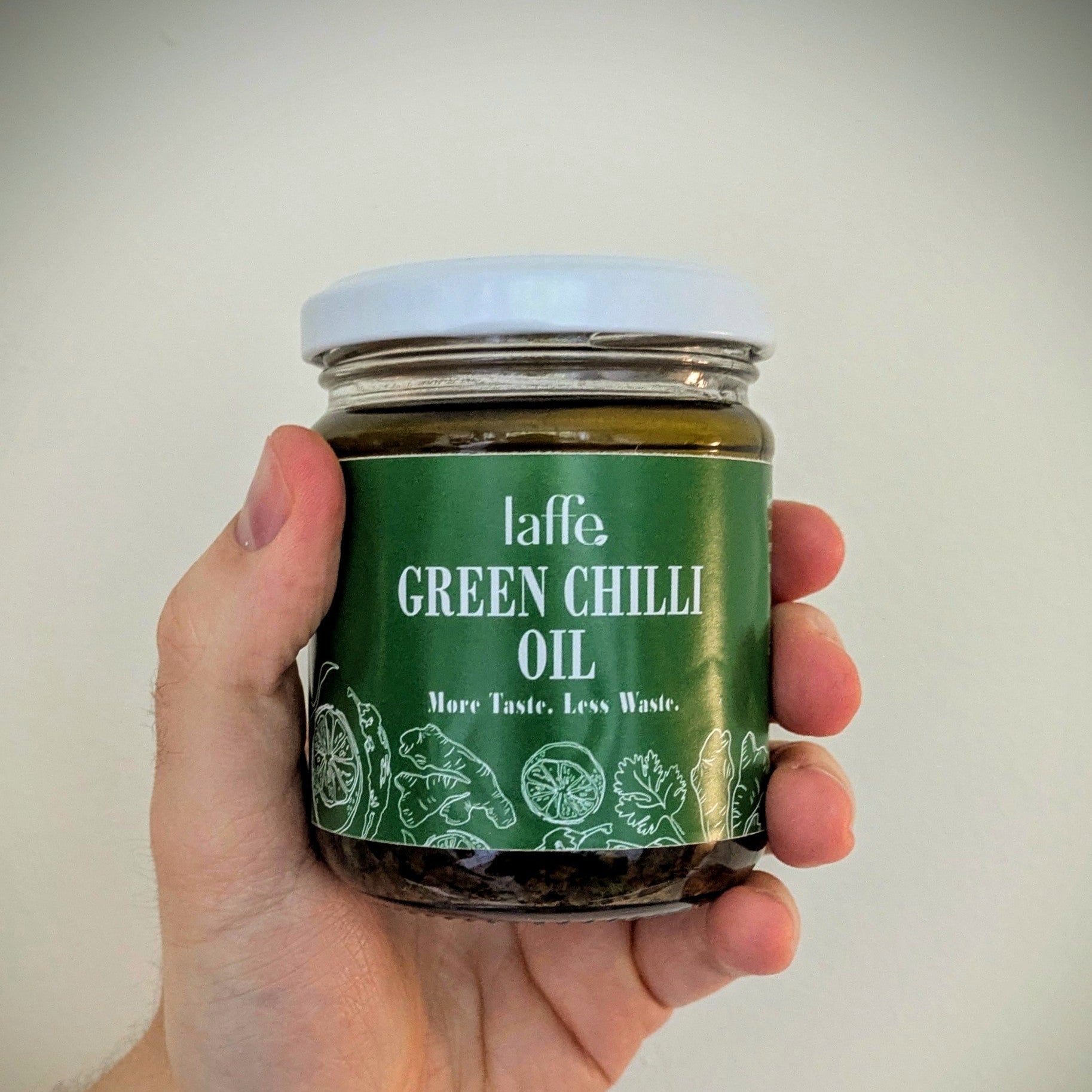 Hand holding a jar of Laffe Green Chilli Oil against a plain background