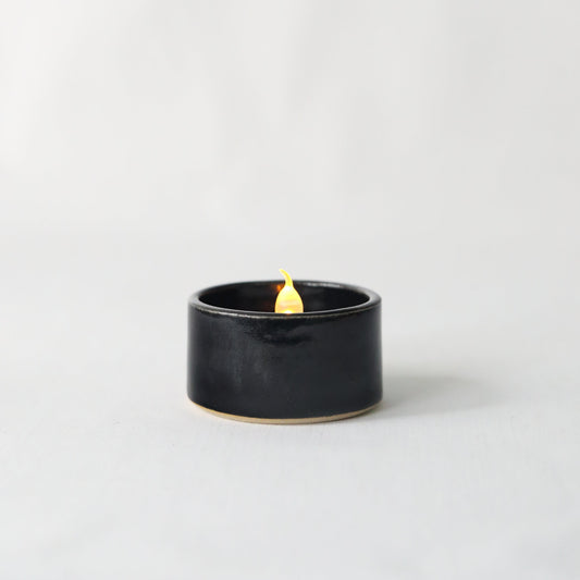 Handmade jet black ceramic tea light holder by Katie L Thompson Designs, featuring a sleek, minimalist design for ambient lighting.