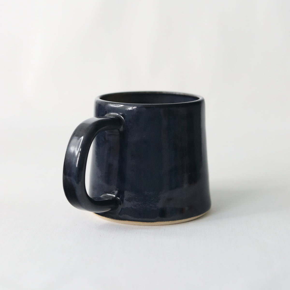Handmade black ceramic standard mug by Katie L Thompson Designs, featuring a sleek jet black finish and classic shape.