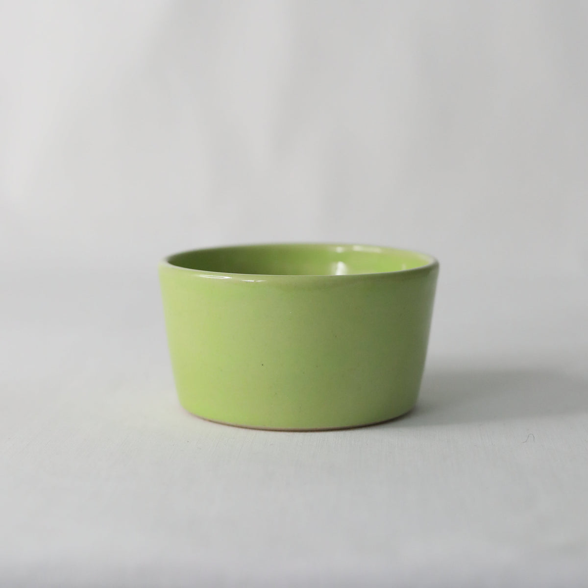 Handmade spring green ceramic side bowl by Katie L Thompson Designs, showcasing its vibrant color and decorative shape.