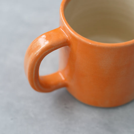Handmade ceramic pint mug with a vibrant mandarin orange design by Katie L Thompson Designs