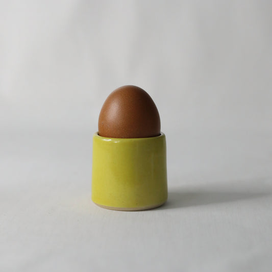 Handmade sun yellow ceramic egg cup by Katie L Thompson Designs, featuring a classic egg holder with a smooth, vibrant yellow finish.