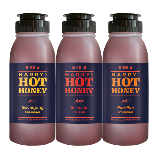 Three Harry's Hot Honey Fusion sauces in gochujang, sriracha, and Thai flavors in glass bottles with colorful labels.